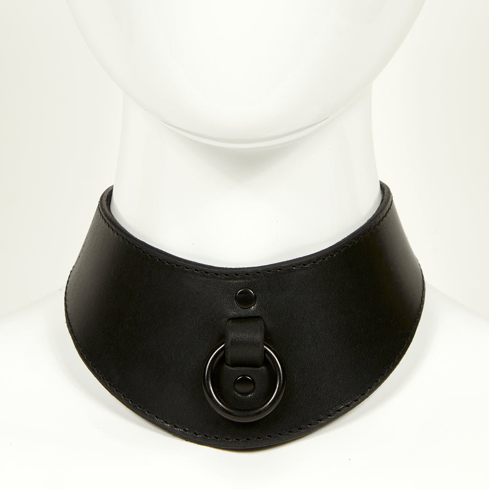 
                  
                    NAOMI COLLAR front view of wide, curved style collar in black leather with black stitched edges, black o-ring suspended from a strap tucked into collar, riveted with black hardware
                  
                