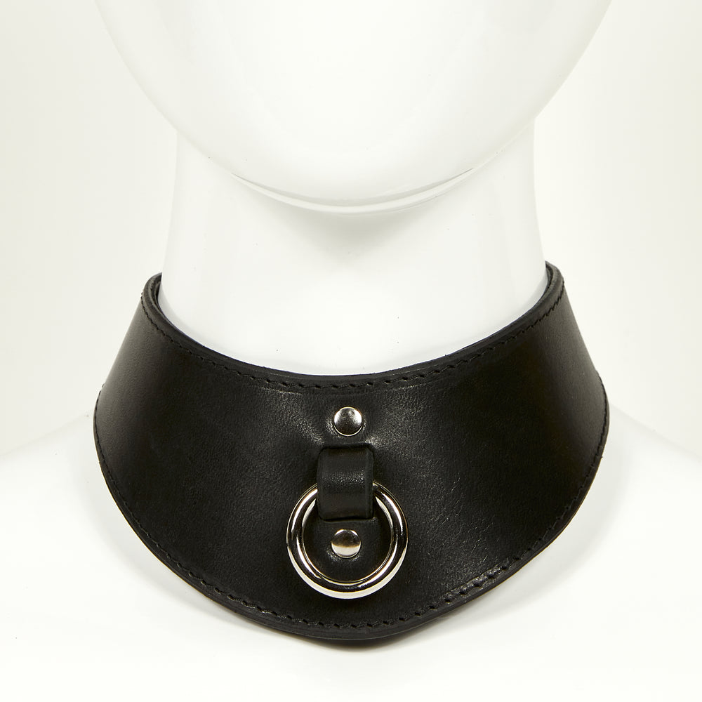 
                  
                    NAOMI COLLAR front view of wide, curved style collar in black leather with black stitched edges, silver o-ring suspended from a strap tucked into collar, riveted with silver hardware
                  
                