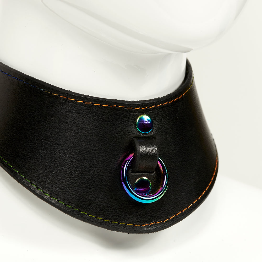 NAOMI COLLAR closeup 3/4 front view of wide, curved style collar in black leather with rainbow stitched edges, rainbow o-ring suspended from a strap tucked into collar, riveted with rainbow hardware